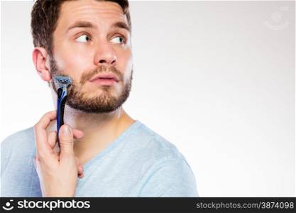 Health beauty and skin care concept. Closeup of male face. Young man guy styling beard holding disposable blue razor blade white background.
