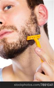 Health beauty and skin care concept. Closeup of male face. Young man guy styling beard holding disposable yellow razor blade white background.