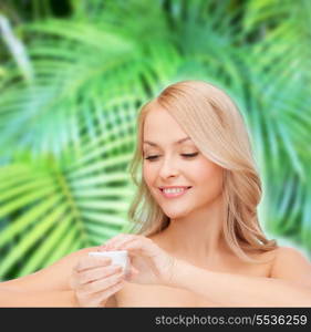 health, beauty and spa concept - beautiful woman applying cream