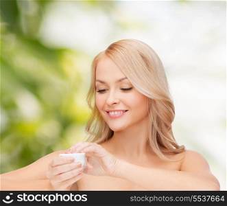 health, beauty and spa concept - beautiful woman applying cream