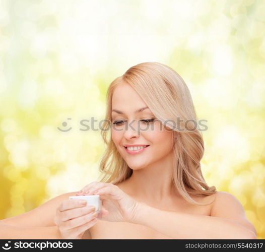 health, beauty and spa concept - beautiful woman applying cream