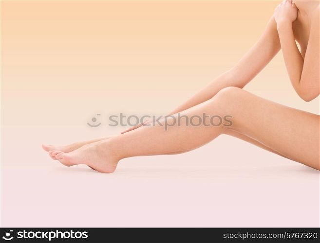 health, beauty, bodycare and people concept - naked woman legs over beige background
