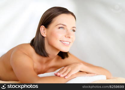 health, beauty, resort and relaxation concept - beautiful woman in spa salon lying on the massage desk