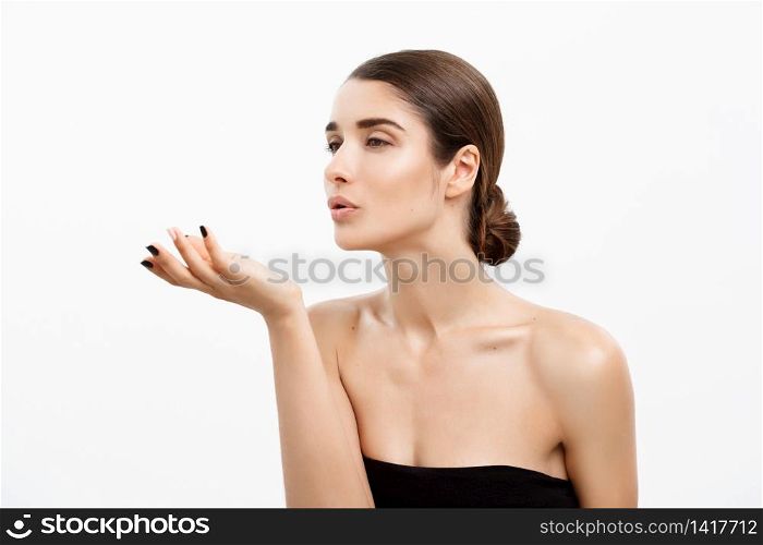 Health care and spa concept - attractive young and healthy woman blowing a kiss from her hand white background. Health care and spa concept - attractive young and healthy woman blowing a kiss from her hand white background.