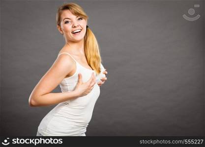 Health care, bosom concept. Young happy joyful woman wearing tshirt holding hands on breast and pushing them up. Joyful woman holding hands on her breast