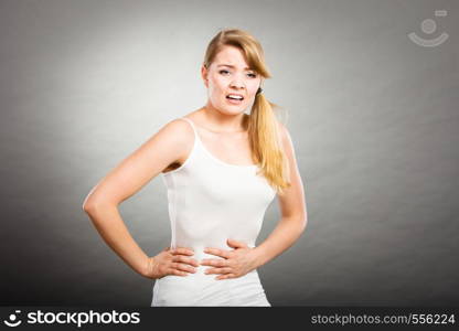 Health care concept. Bellyache, indigestion or menstruation. Young female suffering from strong stomach ache abdominal pain on gray. Woman suffer from belly pain.