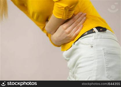 Health care concept. Bellyache, indigestion or menstruation. Young unrecognizable female suffering from strong stomach ache abdominal pain on gray. Woman suffer from belly pain.
