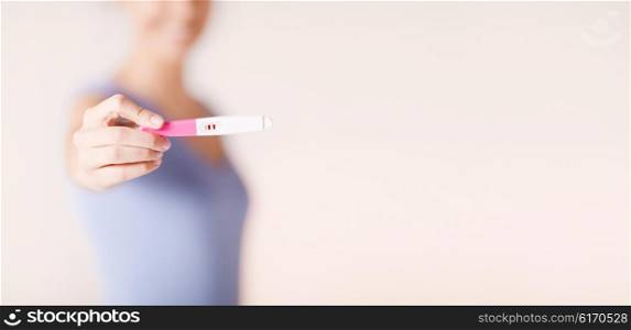 health care concept - close up of happy woman holding and showing pregnancy test. happy woman with pregnancy test