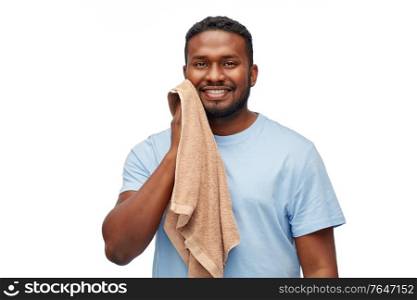 health care, dental hygiene and people concept - smiling african american young man wiping his face with bath towel over white background. african american man wiping face with bath towel