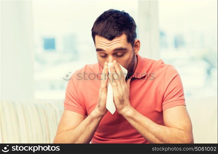 health care, flu, allergy, hygiene and people concept -sick man blowing nose to paper napkin at home. sick man blowing nose to paper napkin at home