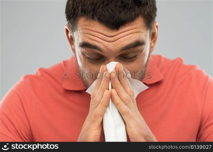 health care, flu, allergy, hygiene and people concept -sick man blowing nose to paper napkin at home