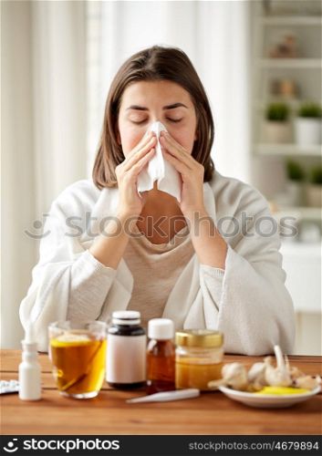 health care, flu, hygiene, age and people concept - sick woman with medicine blowing nose to paper wipe at home