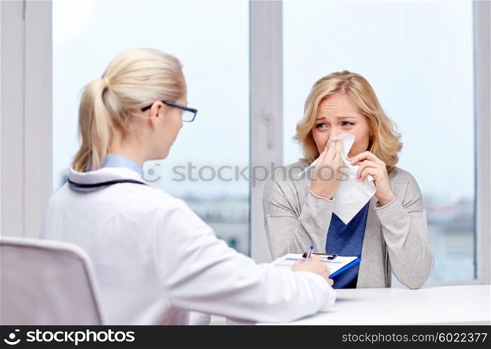 health care, flu, hygiene and people concept - doctor talking to ill woman blowing nose to paper napkin patient at hospital