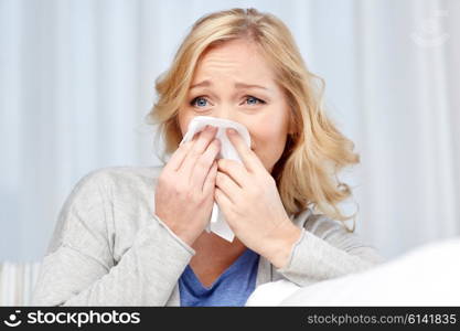 health care, flu, hygiene and people concept - ill woman blowing nose to paper napkin