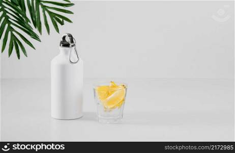 Health care, healthy food and drink concept. Fresh cool lemon water in a bottle and in a glass. Fitness shake, detox drink or lemonade. Selective focus with copy space