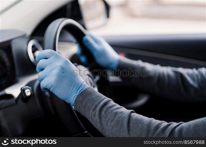 Health care in transport concept. Unrecognizable driver wears rubber protective gloves protects from coronavirus drives car during epidemic. Covid-19 protection concept. Disease, infection, quarantine