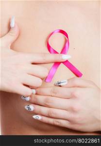 Health care medical concept. Closeup naked woman with pink breast cancer awareness ribbon, female checking her breasts for lumps