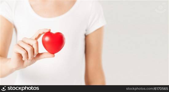 health care, medicine and charity concept - close up of woman holding red heart