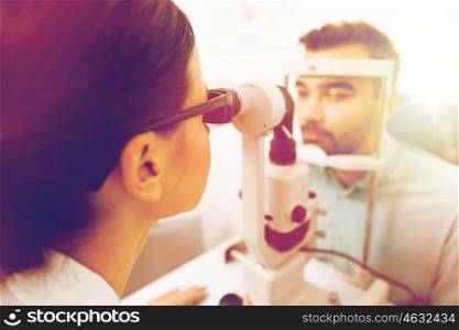 health care, medicine, people, eyesight and technology concept - close up of optometrist with slit lamp checking patient vision at eye clinic or optics store