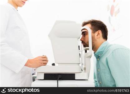health care, medicine, people, eyesight and technology concept - close up of optometrist with autorefractor checking patient vision at eye clinic or optics store