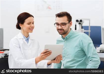 health care, medicine, people, eyesight and technology concept - female optician with tablet pc computer and man in glasses at eye clinic or optics store