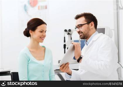 health care, medicine, people, eyesight and technology concept - optician in glasses with tablet pc computer and patient at eye clinic or optics store