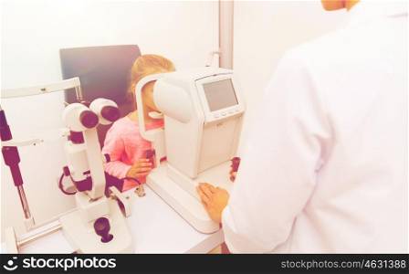 health care, medicine, people, eyesight and technology concept - optometrist with autorefractor checking patient vision eye clinic or optics store