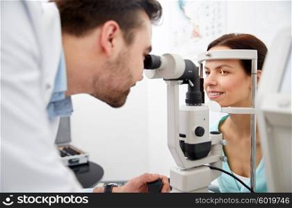 health care, medicine, people, eyesight and technology concept - optometrist with non contact tonometer checking patient intraocular pressure at eye clinic or optics store