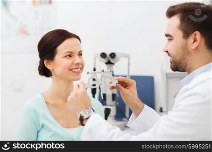 health care, medicine, people, eyesight and technology concept - optometrist with trial frame checking patient vision at eye clinic or optics store