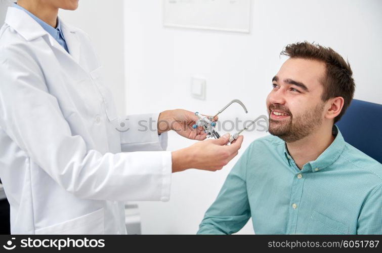 health care, medicine, people, eyesight and technology concept - optometrist with trial frame checking patient vision at eye clinic or optics store