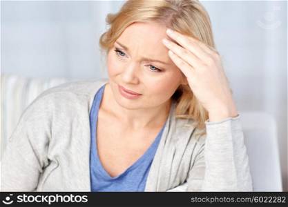 health care, pain, stress and people concept - middle aged woman suffering from headache at home