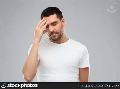 health care, pain, stress and people concept - young man suffering from headache