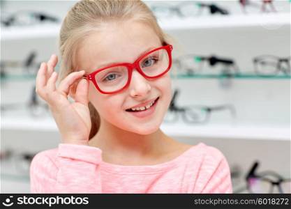 health care, people, eyesight and vision concept - little girl in glasses at optics store