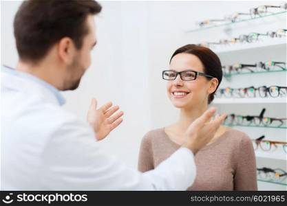 health care, people, eyesight and vision concept - optician and woman in glasses at optics store