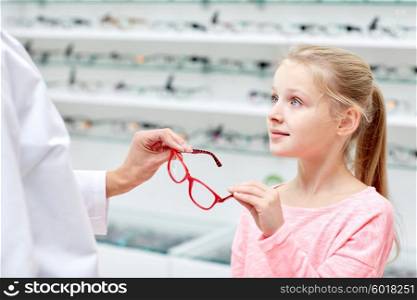health care, people, eyesight and vision concept - optician giving glasses to little girl at optics store