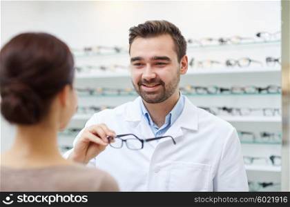 health care, people, eyesight and vision concept - optician giving glasses to woman at optics store