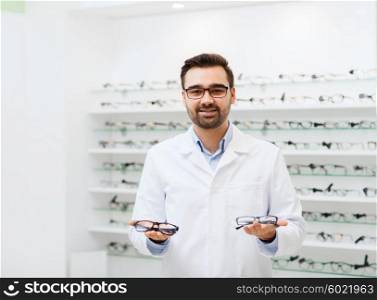 health care, people, eyesight and vision concept - smiling man optician holding glasses at optics store