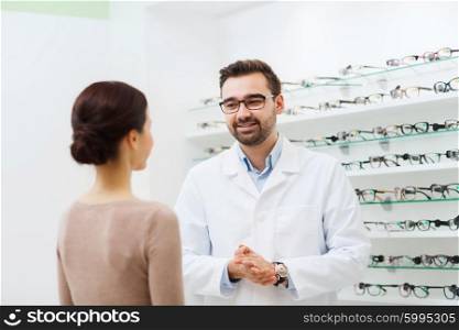health care, people, eyesight and vision concept - woman and optician in glasses talking at optics store