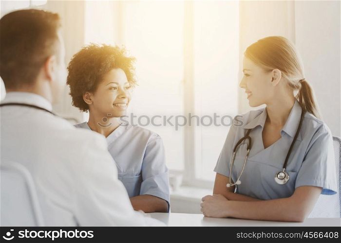 health care, profession, people and medicine concept - group of happy doctors or nurses meeting and talking at hospital