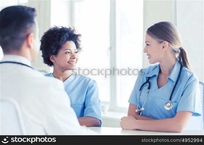 health care, profession, people and medicine concept - group of happy doctors or nurses meeting and talking at hospital. group of happy doctors meeting at hospital office