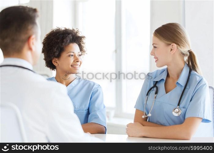 health care, profession, people and medicine concept - group of happy doctors or nurses meeting and talking at hospital