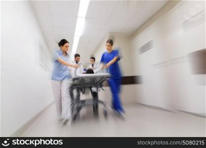 health care, reanimation and medicine concept - group of medics or doctors carrying unconscious woman patient on hospital gurney to emergency (motion blur effect). medics and patient on hospital gurney at emergency