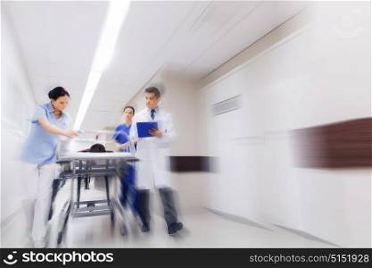 health care, reanimation and medicine concept - group of medics or doctors carrying unconscious woman patient on hospital gurney to emergency (motion blur effect). medics and patient on hospital gurney at emergency
