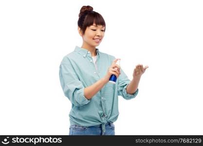 health care, safety and people concept - happy smiling asian woman using hand sanitizer over white background. happy smiling asian woman using hand sanitizer
