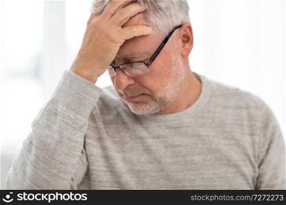 health care, stress, old age and people concept - senior man suffering from headache at home. senior man suffering from headache at home