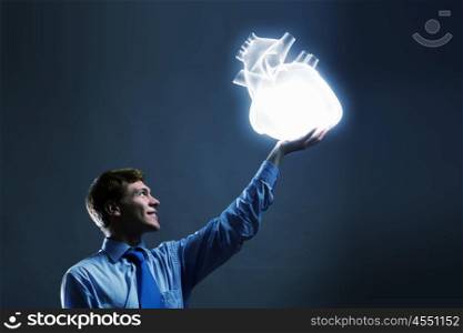 Health care. Young man holding human heart in palm