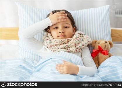 health, children and people concept - sick little girl lying in bed at home. sick little girl lying in bed at home