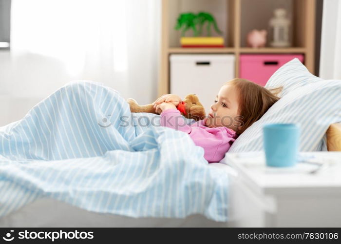 health, children and people concept - sick little girl lying in bed at home. sick little girl lying in bed at home