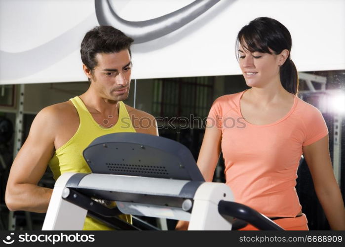 health club: woman walking on a tapis roulant with her personal trainer