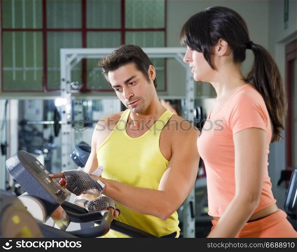 health club: woman walking on a tapis roulant with her personal trainer